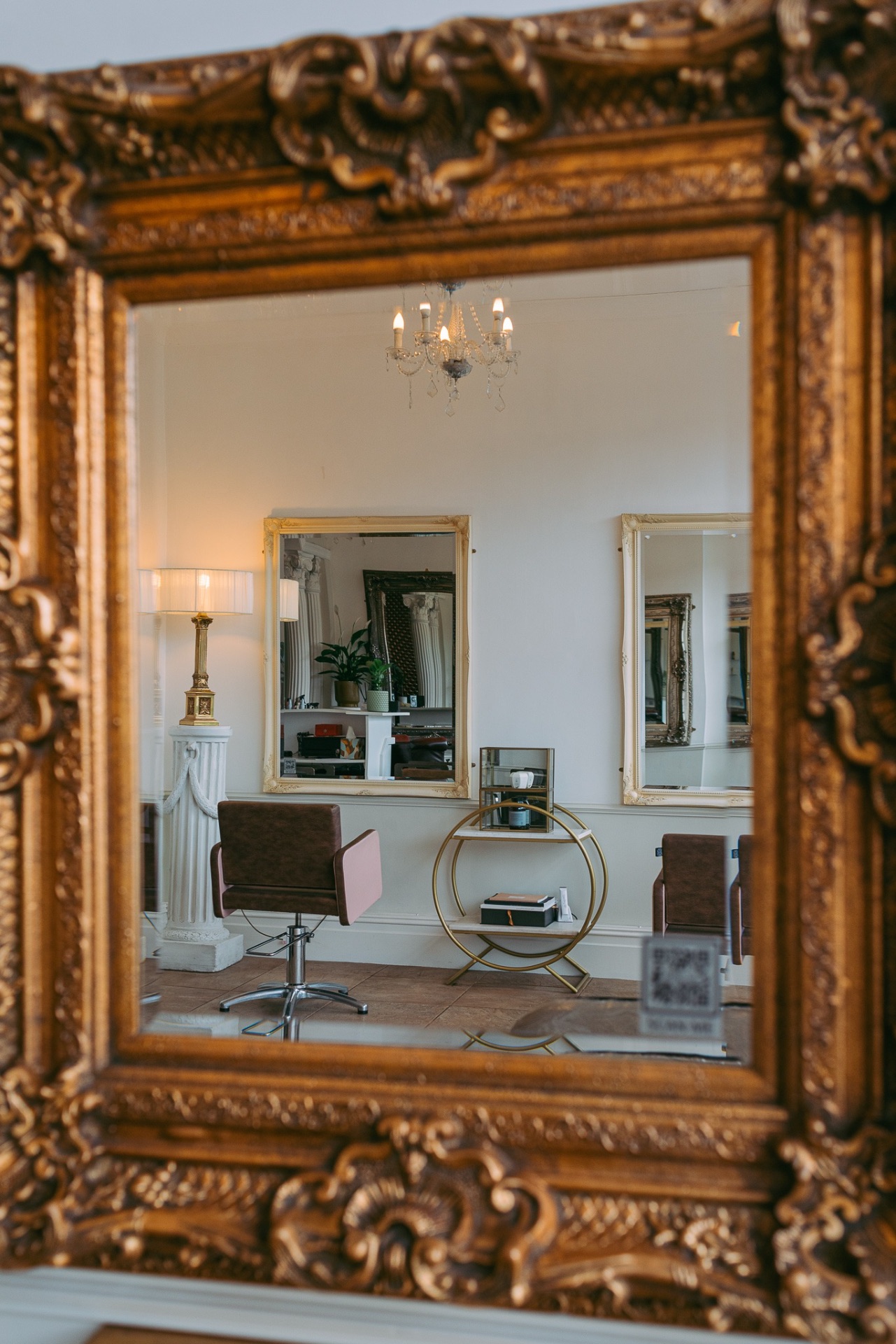 Ornate gilded mirror reflecting the salon interior